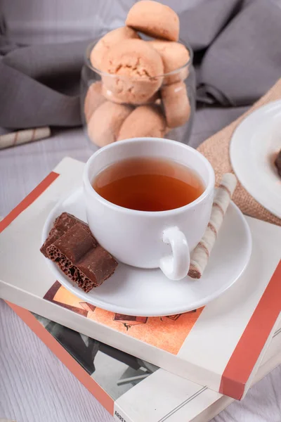 Book,cup of tea and chocolate on the table — Stock Photo, Image