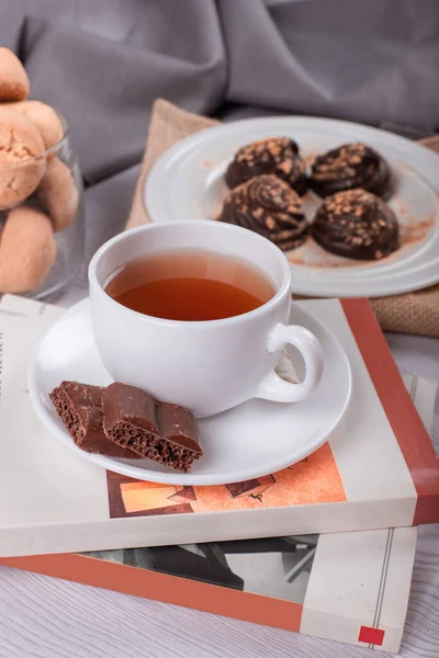 Book,cup of tea and chocolate on the table — Stock Photo, Image