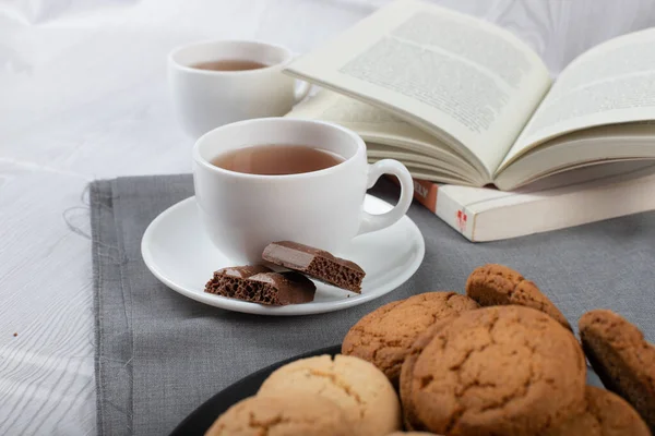 Livre, tasse de thé et chocolat sur la table — Photo