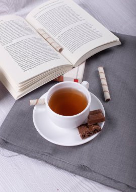 Kitap, çay ve çikolata masada.