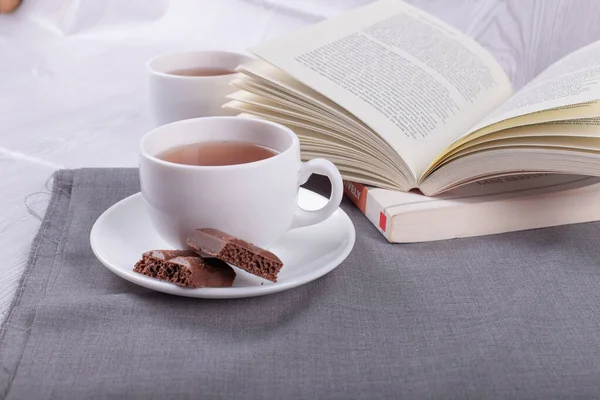 Livre, tasse de thé et chocolat sur la table — Photo