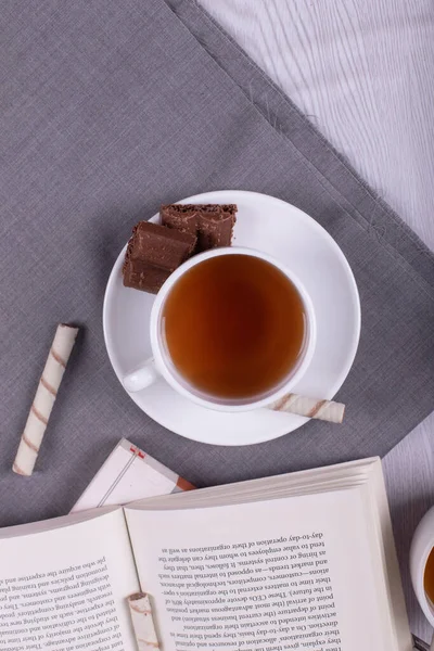 Libro, Dulces bocadillos y taza de té en la mesa — Foto de Stock
