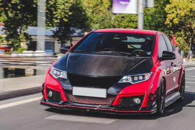 Kırmızı spor sedan, siyah otototonom yolda.