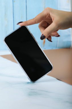 Parmağıyla siyah bir akıllı telefonu alıyor.