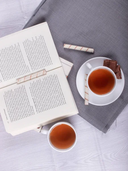 Book, Sweet snacks and cup of tea on the table — Stock Photo, Image