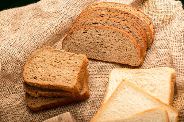 Snijwonden van donker en wit brood op het keukenbord — Stockfoto