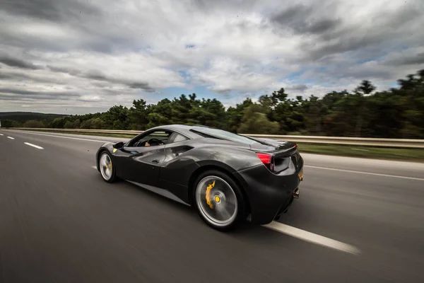 雲の下の高速道路で黒いスポーツモデルの車の運転、後ろからの眺め — ストック写真