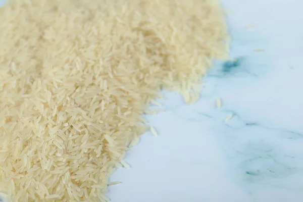 Droge en verse Aziatische rijst aan de linkerkant van het blauwe marmer — Stockfoto