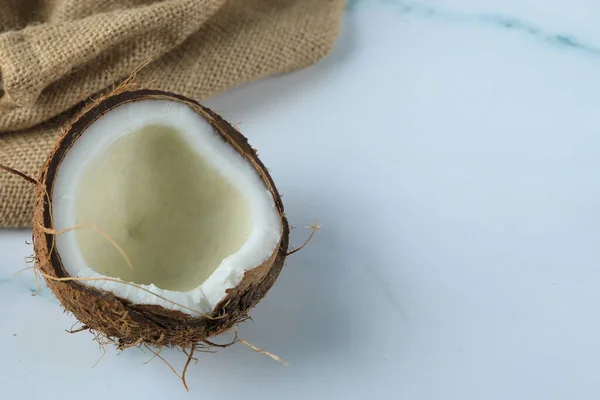 Fruta de coco meio quebrada em um mármore em um pedaço de serapilheira — Fotografia de Stock