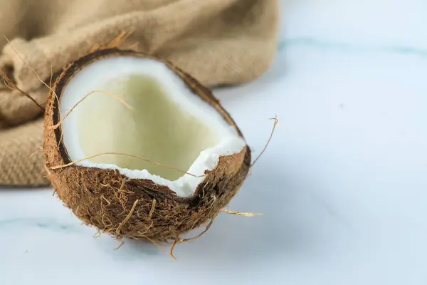 Fruta de coco meio quebrada em um mármore — Fotografia de Stock