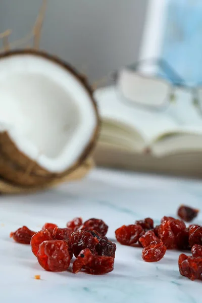 Halbe Kokosfrucht mit roten trockenen Beeren auf einem Marmor — Stockfoto