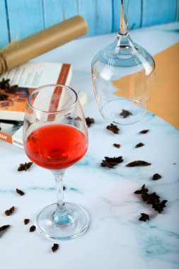 Bardakta kırmızı bir gül ve mavi mermerde boş bir bardak.