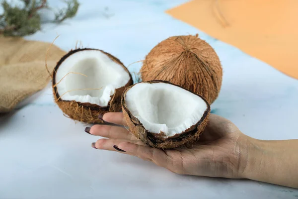 Hald mit ganzen Kokosfrüchten in der Hand auf blauem Hintergrund — Stockfoto