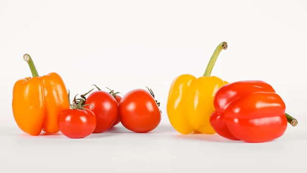 Pimentos vermelhos e amarelos com tomates em branco — Fotografia de Stock