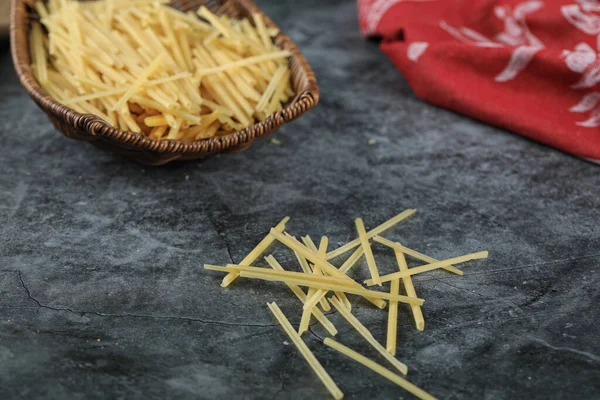 Zelfgemaakte verse spaghetti in de mand schotel op de linker bovenhoek van de achtergrond — Stockfoto