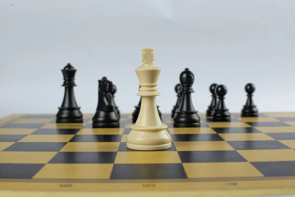 Biały król przeciwko czarnej pełnej drużynie na szachownicy — Zdjęcie stockowe