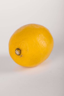 Beyaz arka planda gölgesi olan taze sarı bir limon.
