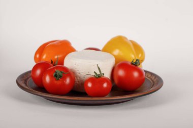 Kahverengi tabakta peynir, domates ve biber.