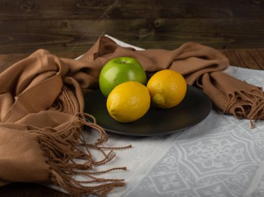 Siyah bir tabakta limon ve elma. 
