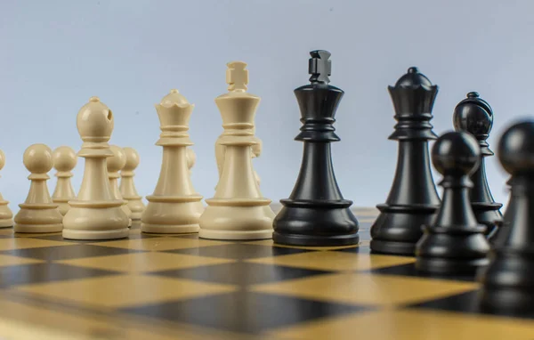 İzole edilmiş beyaz arka planda satranç tahtasındaki siyah ve beyaz figürler — Stok fotoğraf
