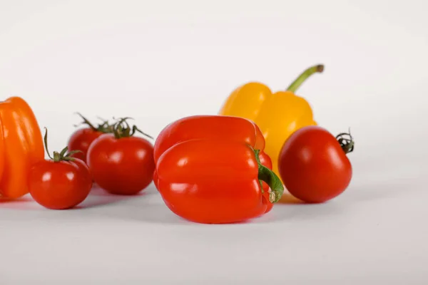 Tomates vermelhos e pimentas em um fundo branco com sombras — Fotografia de Stock
