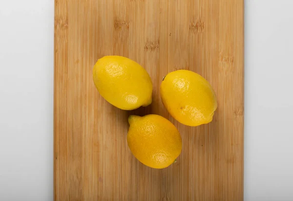 Three lemons on a wooden board — Stock Photo, Image