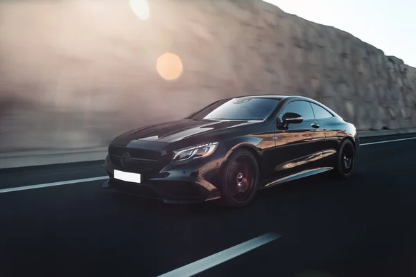 Güneş ışığının altında siyah spor sedan