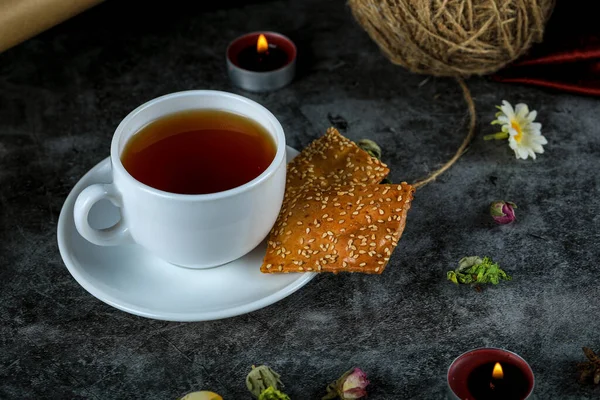 Чашка чая с крекерами на черном мраморе — стоковое фото