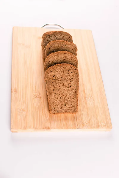 Donker brood plakjes op een houten plaat geïsoleerd op wit — Stockfoto