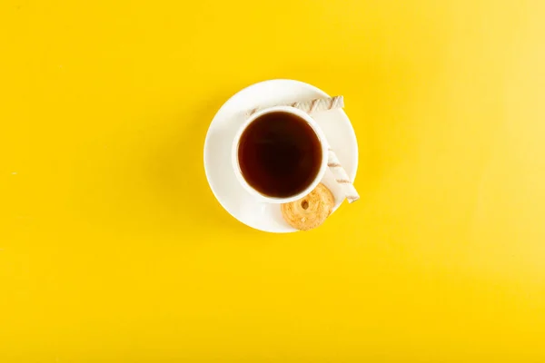 A cup of tea with biscuit on a yellow background. top view — Stock Photo, Image
