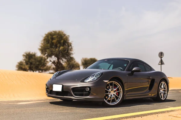 Çölde, güneşin altında gri renkli bir spor araba sürüyorum.