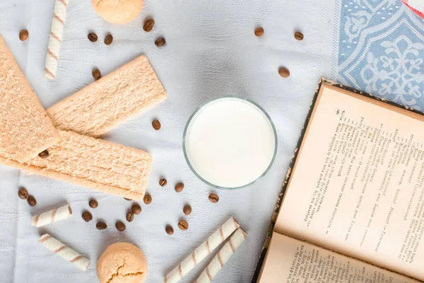 Cracker bread and cookies with a glass of milk and a book aside — Stock Photo, Image