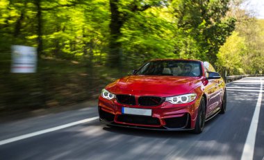 Yeşil kırsal yolda kırmızı lüks bir süvari.