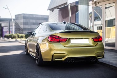 Kırmızı ksenon ışıkları olan altın renkli lüks araba.