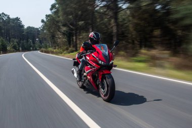 Orman yolunda kırmızı motorsikletli, yüksek hızlı.