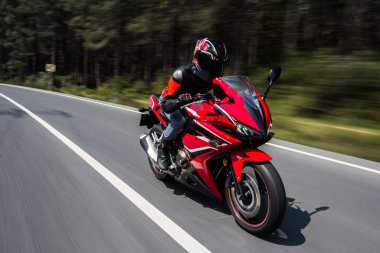 Ormanda kırmızı bir motosiklet sürmek vites ve miğferle, ön manzara