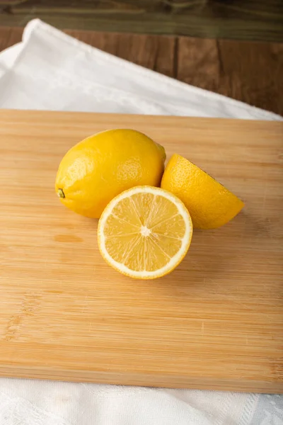 Напіврізані і цілі шматочки лимона на дерев'яній дошці — стокове фото