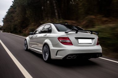 Otobanda Whitesport Sedan, doğada, ormanda araba sürüyor.