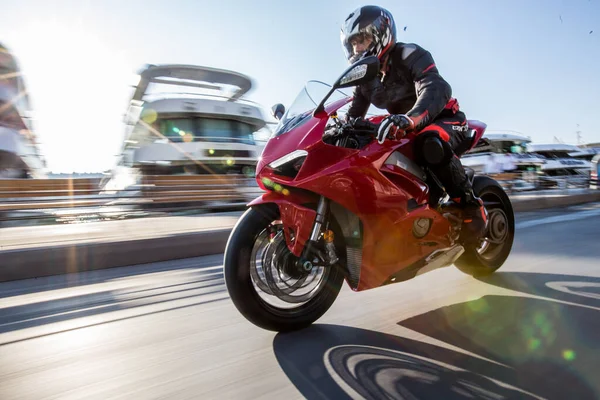 A biker in gear and helmet biking a red motorcycle — Stock Photo, Image