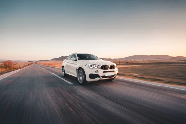 Kırmızı ksenon ışıklı beyaz sedan araba yolda gidiyor. ön görünüm