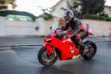 Caddede kırmızı motosiklet kullanan bir motorcu.