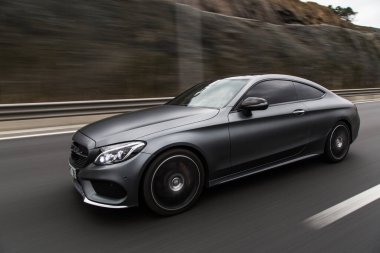 Gümüş krom spor sedan yolda gidiyor.