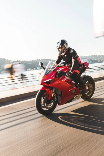 A biker in gear and helmet biking a red motorcycle in the port — Stock Photo, Image