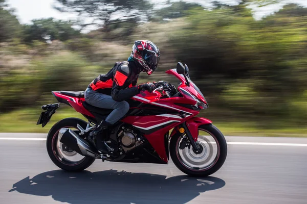 Faire du vélo une moto rouge dans la route forestière en équipement et casque — Photo