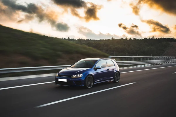 Bulutlu bir havada siyah araba yolda.