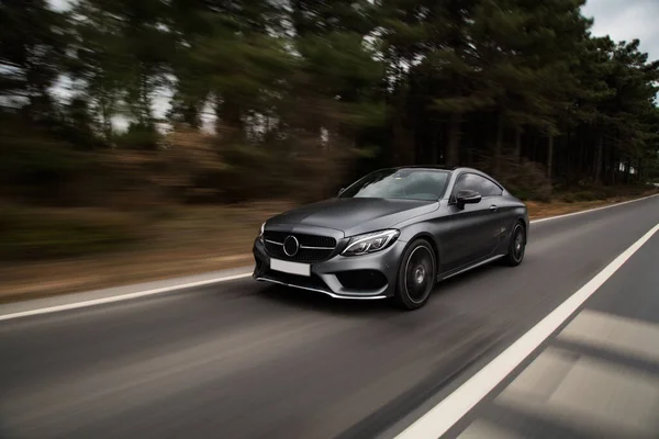 Gümüş krom spor sedan yolda gidiyor. Ksenon ışıkları. ön görünüm