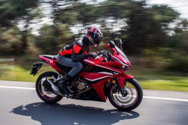 Orman yolunda kırmızı bir motosiklet sürüyorum.