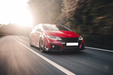 Kırmızı coupe güneş ışığının altında yolda gidiyor.