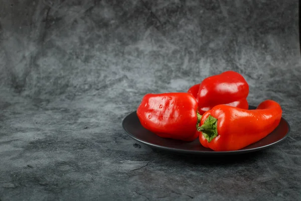 Červené chilli papričky v černém talíři. — Stock fotografie
