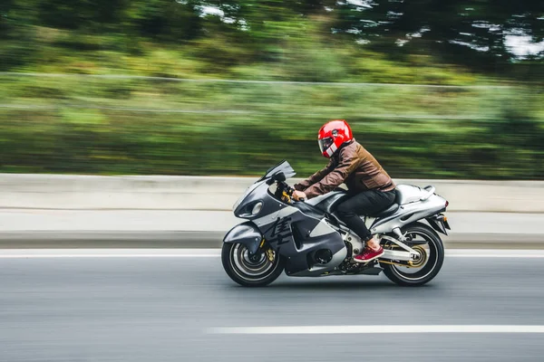 Biker with a red helmet biking a motorcycle. profile view — Stock Photo, Image